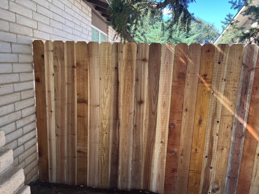 Western Redwood dogeared picket fence with oil pipe post painted black. Clovis NM